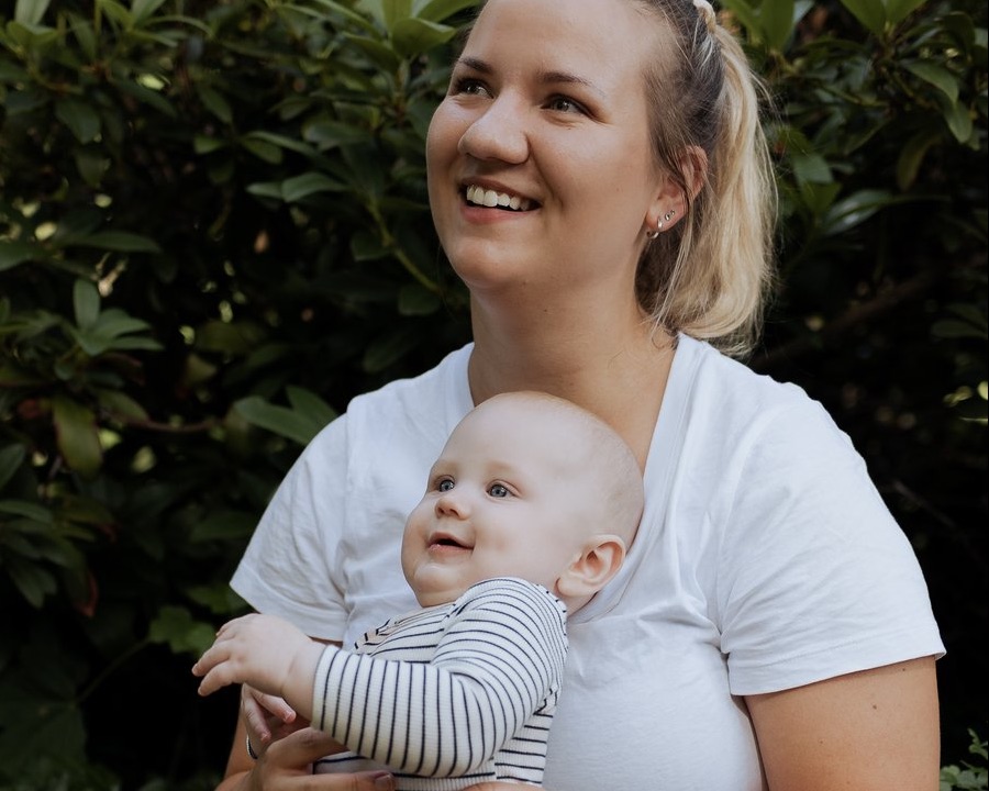 Hebamme Tina mit einem Baby auf dem Arm